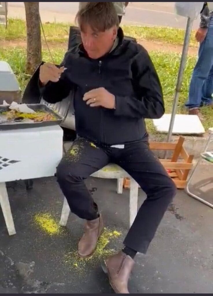Ex-presidente comendo churrasco e farofa, se lambuzando, derramando a comida no colo e no chão | Foto: Reprodução